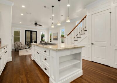 Bright, freshly painted kitchen with white cabinetry and hardwood floors after restoration.