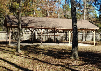 Metal building structure in a wooded backyard before cleanup or renovation.