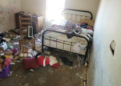 bedroom filled with clutter and household items before hoarding cleanup