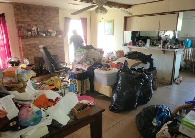 living room and kitchen filled with clutter before hoarding cleanup